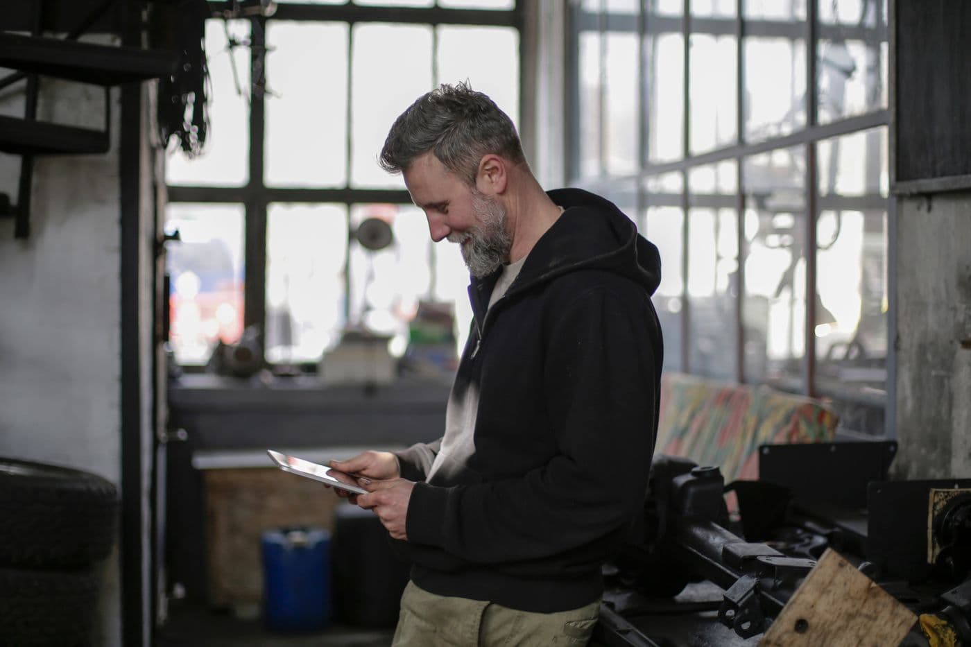 A tradesperson checking job details on a tablet in a workshop.